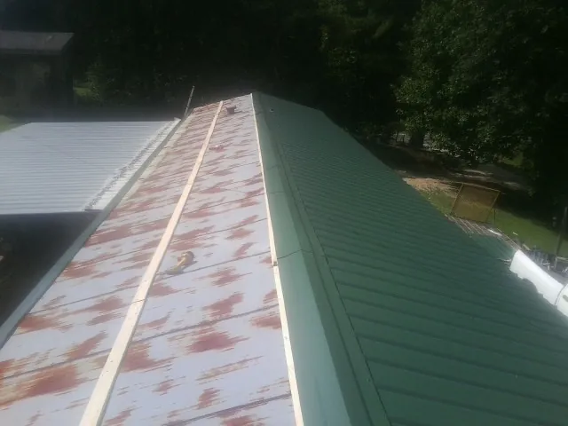 Old rusted panels beside newly installed green metal roofing — Wind Damage Roof Repair by Roofing Brothers in Williams Bay
