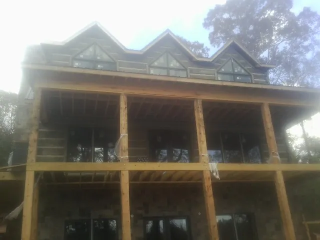 Dormers and porch framing on a large log home under construction — Roof Coating work by our crew in Williams Bay