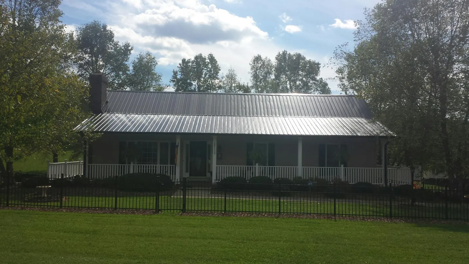 Gray metal roof on a brick ranch with a full width front porch — Gutter Guard Installation work by our crew in Williams Bay