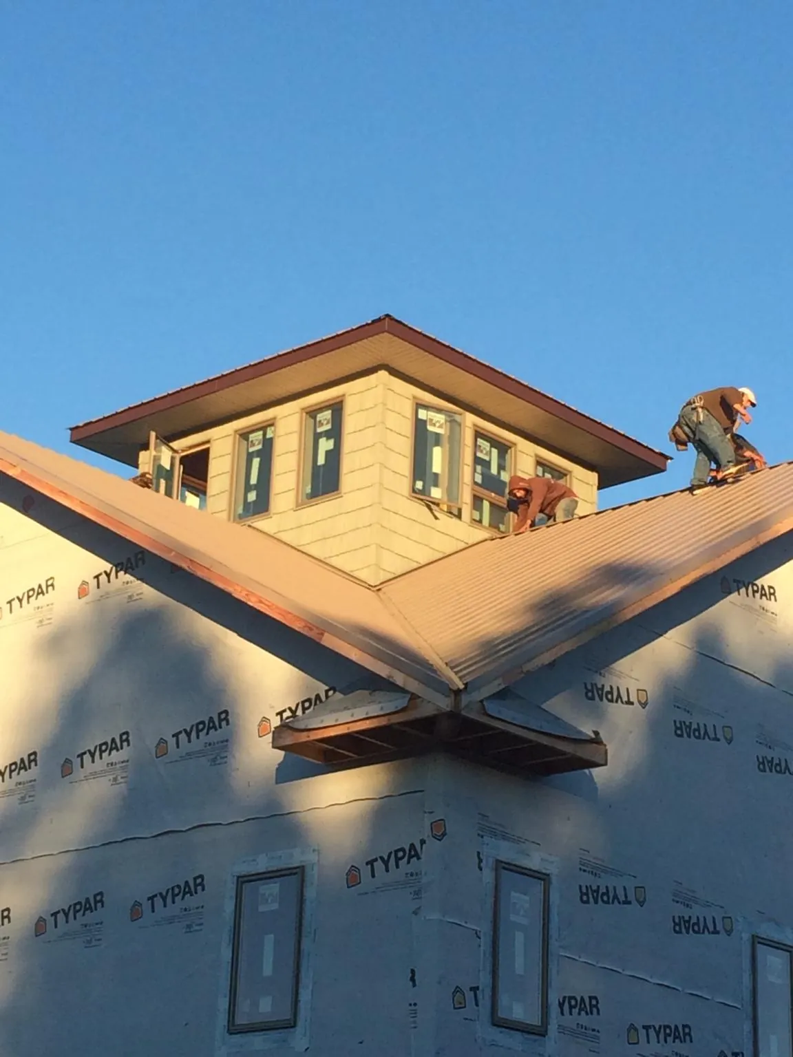 Roofers working around a rooftop cupola on a new metal roof at sunset — Roof Waterproofing in Williams Bay by Roofing Brothers